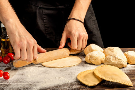 The cook prepares pasties. Step-by-step instruction. Forms the dough. Wooden background. Copy space.