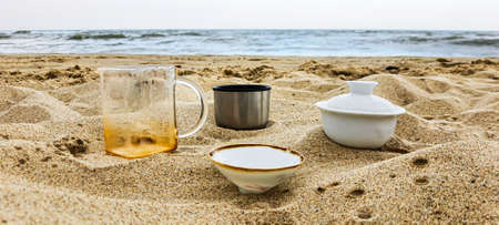Seaside. Dishes with tea on the sand. Summer vacation. Sunset.の写真素材