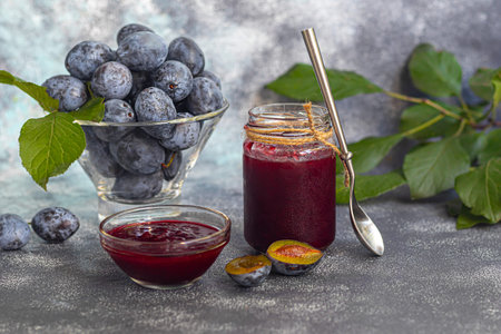 Plum jam in a jar. In the background there are plums. Tkemali sauce. Preparing for winter. Light background. Copy space.の写真素材