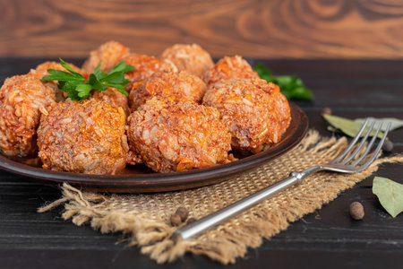 Meat balls on a wooden background with sage and parsley leaves. Homemade lunch. Copy space.
