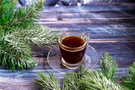 A cup of aromatic coffee with brown sugar, Christmas decorations, branches of a Christmas tree. Holiday concept New Year. On a wooden background. Copy space.の写真素材