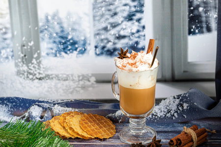 Hot coffee latte with cinnamon sticks, sprinkled with cinnamon. Christmas decorations, branches of a...