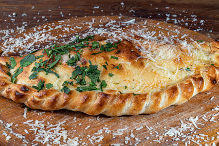 Pizza calzone with bacon and cheese, herbs and cherry tomatoes. With mozzarella, shrimps and octopuses, mussels and other products on a wooden background. copyspace.の写真素材
