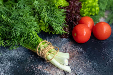 Fresh vegetables for salad. Tomatoes and lettuce, cucumbers with zucchini and cabbage with dill. Spring harvest, benefits and vitamins. On a dark background.の写真素材