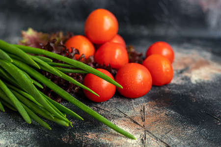 Fresh vegetables for salad. Tomatoes and lettuce, cucumbers with zucchini and cabbage with dill. Spring harvest, benefits and vitamins. On a dark background.の写真素材