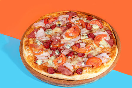 Pizza with bacon cheese and herbs on a wooden plate with cheese and cherry tomatoes. On a colored background. copy spaceの写真素材