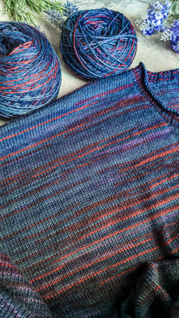 Handmade knitted products. Knitted cardigan made of purple and red threads. Gray background. Copy spaceの写真素材