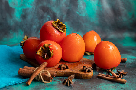 Persimmon on a dark background. Fresh, ripe fruits on a blue plate and in a box. Healthy eating.の写真素材