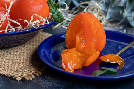 Persimmon on a dark background. Fresh, ripe fruits on a blue plate and in a box. Healthy eating.の写真素材
