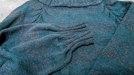Handmade knitted products. Knitted fabric made of dark threads. Woman pullover. Copy space