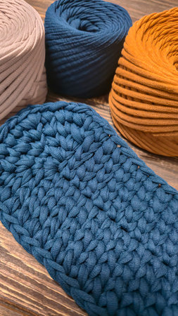 The bottom of the bag is crocheted from blue knitted yarn. On a wooden background. Handmade.