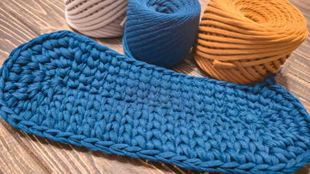 The bottom of the bag is crocheted from blue knitted yarn. On a wooden background. Handmade.
