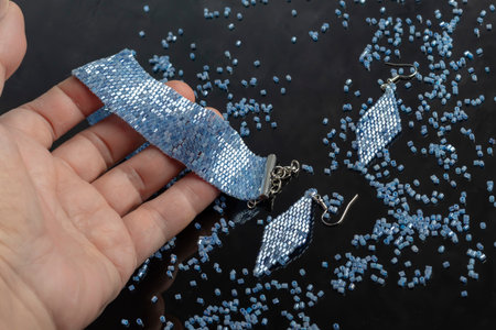 Bracelet and earrings made of beads on a light background. Handmade. Jewelry and decor. Weaving from glass beads.の写真素材