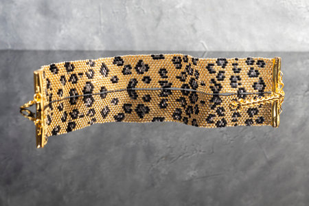 A gold bracelet with a leopard print on a light background. Jewelry.