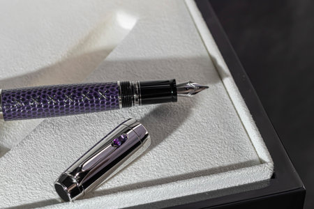 A fountain pen on a gray marble background. A box and case are nearby. A gift set. Office interior.