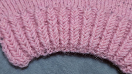 Knitting patterns for sweaters, hats, and other items using light-colored yarn on a light...