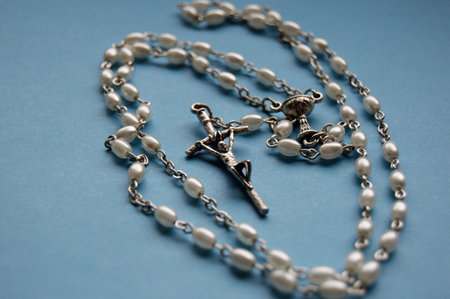 Silver necklace rosary on blue background