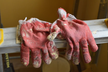 Used red protective gloves lying on the ladder