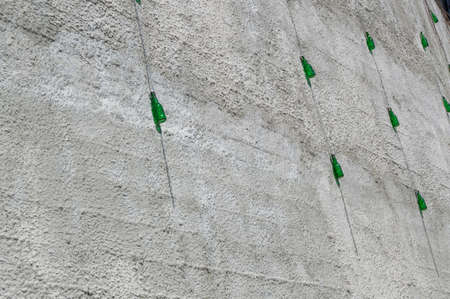 Green glass bottles hanging on a high wall with a chain designed to protect the wallの写真素材