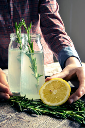 Drink in glass bottles. rosemary, lemon. female handsの写真素材