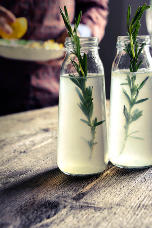 Drink in glass bottles. rosemary, lemon. female handsの写真素材