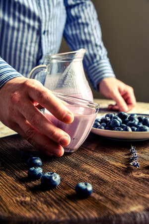 Yogurt in a glass, blueberries, lavender, pitcher. male handsの写真素材