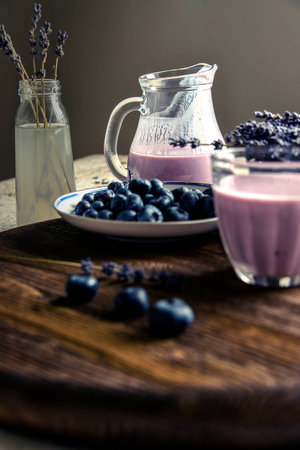 Yogurt in a glass, blueberries, lavender, pitcher. wooden tableの写真素材
