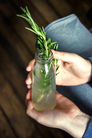 Drink in a glass bottle. rosemary, lemon. female handsの写真素材