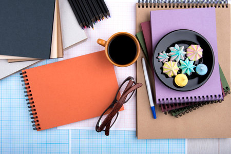Glasses, coffee, meringue, pen, pencil, colored notebooks, top viewの写真素材