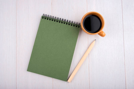 Cup of coffee, green notebook, pencil, overhead viewの写真素材