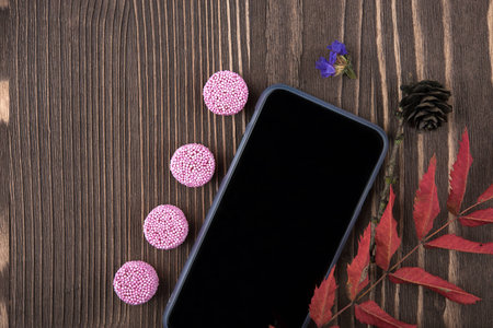 Candy, phone, red autumn leaves, view from aboveの写真素材