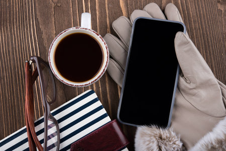 Cup of coffee, gloves, phone, glasses, Notepad in blue stripesの写真素材