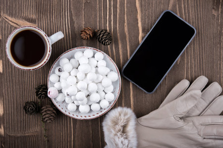 Cup of coffee, cranberries in sugar, cones, gloves, phoneの写真素材