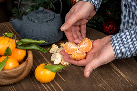 Man cleans the Mandarin. Blue cast iron kettleの写真素材