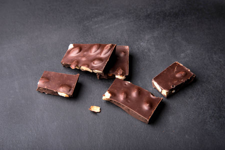 Slices of black chocolate with nuts on a dark background