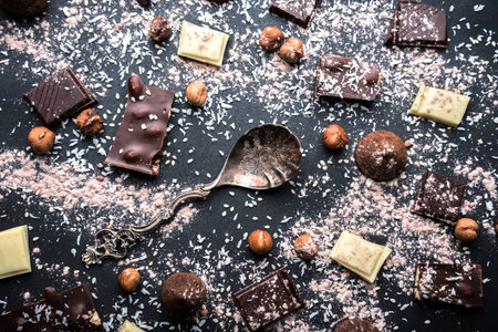 White and dark chocolate on a black background, the nuts and vintage spoon