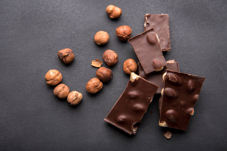 Slices of black chocolate with nuts on a dark backgroundの写真素材