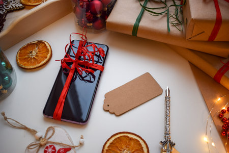 Mobile smartphone tied with a red ribbon surrounded by gifts and other Christmas trifles.の写真素材