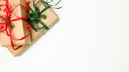 Two Christmas gift boxes packed in kraft and red and green ribbons on a white background, space to insert text, top viewの写真素材