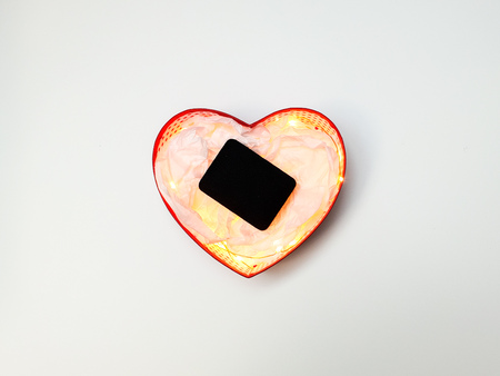 Gift box in the form of a heart with lights inside, a black jewelry box and wrapping paper on a white background, space to insert the name of the companyの写真素材