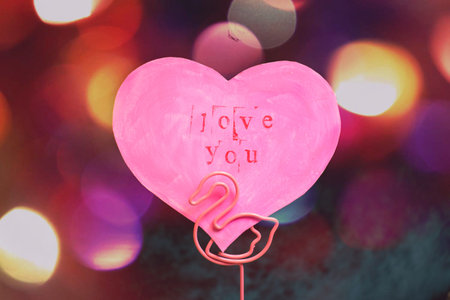 Valentine's Day greeting card in the shape of a pink heart with an inscription love you in a stand...