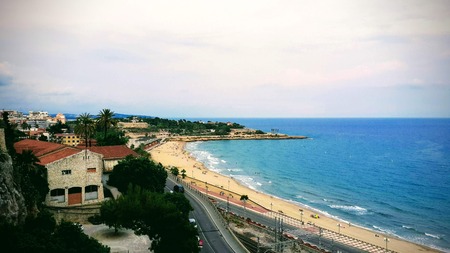 The blue-turquoise sea is washed by a sandy beach on a summer day on the coast of Tarragona, Spainの写真素材