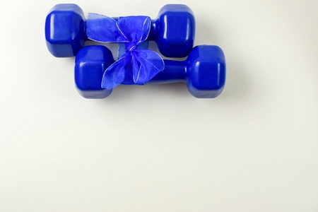 Two blue dumbbells with gift bow on white background, sport and healthy concept, space to insert textの写真素材