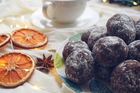 Chocolate gingerbread, sprinkled with powdered sugar on a plate with turquoise leaves, dried oranges, bodyan, a cup of coffee and a garland on a white backgroundの写真素材