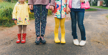 children stand on the asphalt in colorful clothes holding hands