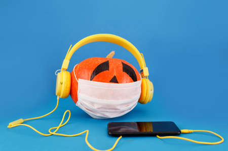 COVID-19 Halloween, a sick pumpkin listens to music in self-isolation.の写真素材