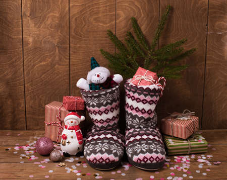 knitted Christmas boots with a pattern, gifts in bright packaging, confetti. new year's still life.の写真素材