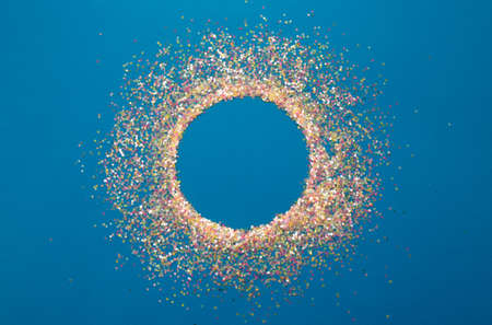 multicolored confetti on a blue background top view.の写真素材