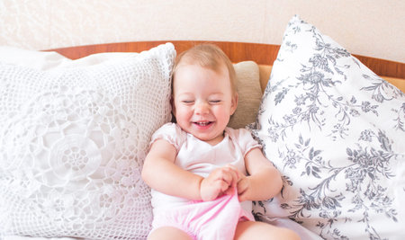 little cute girl playing in bed laughing and smiling.