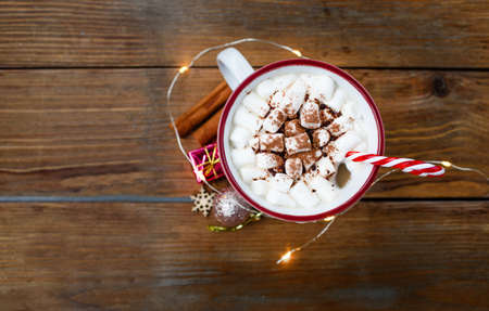 a Cup of hot Christmas drink on a wooden background around a cinnamon stick and Christmas gifts. The view from the topの写真素材